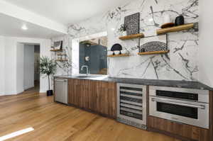 Wet bar featuring wood-finish cabinetry, a stone countertop, and a marble-patterned tile backsplash, appliances virtually staged