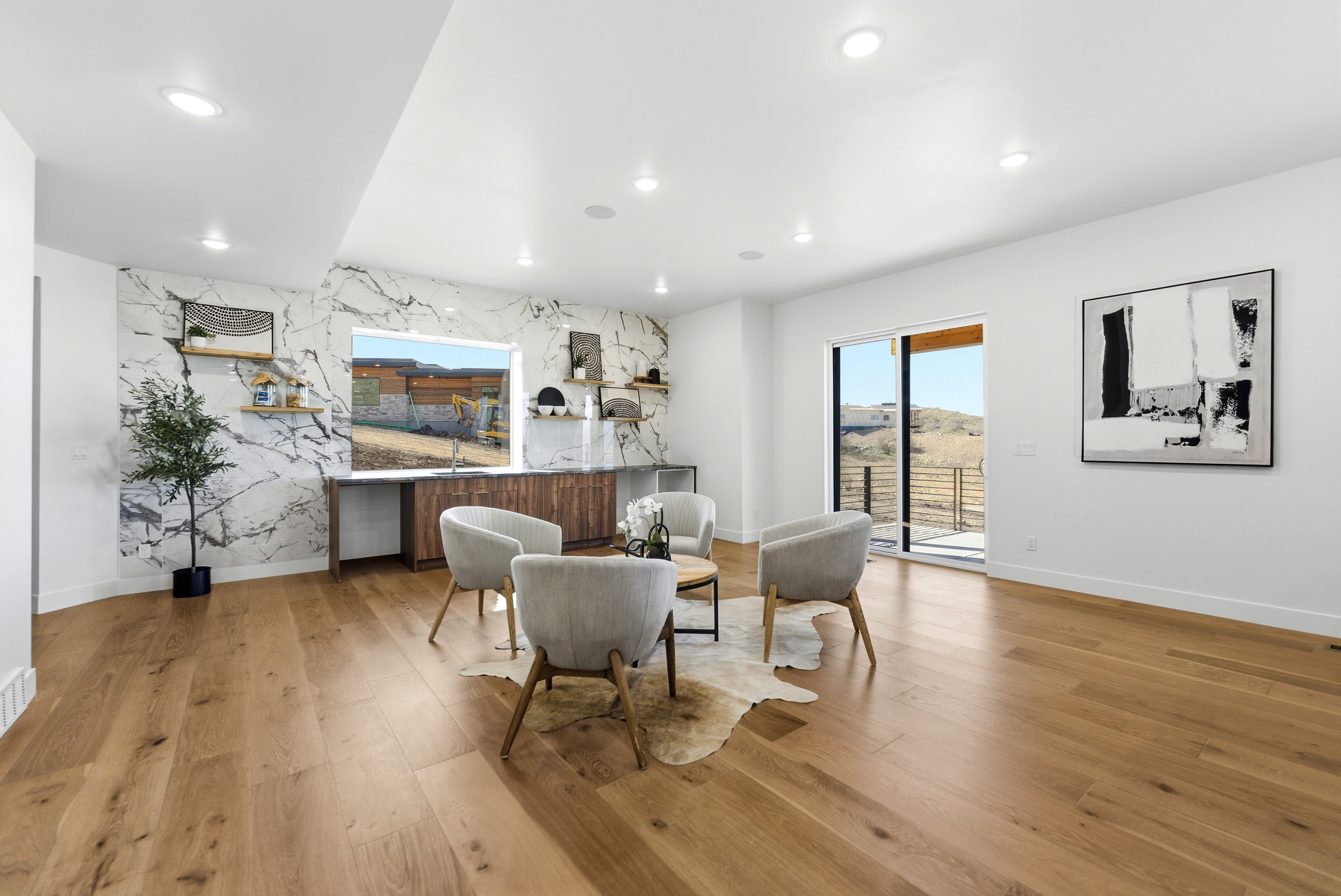 Spacious room featuring wide plank wood flooring, a striking marble-patterned accent wall, recessed lighting, and a built-in wood-finish cabinet with open shelving