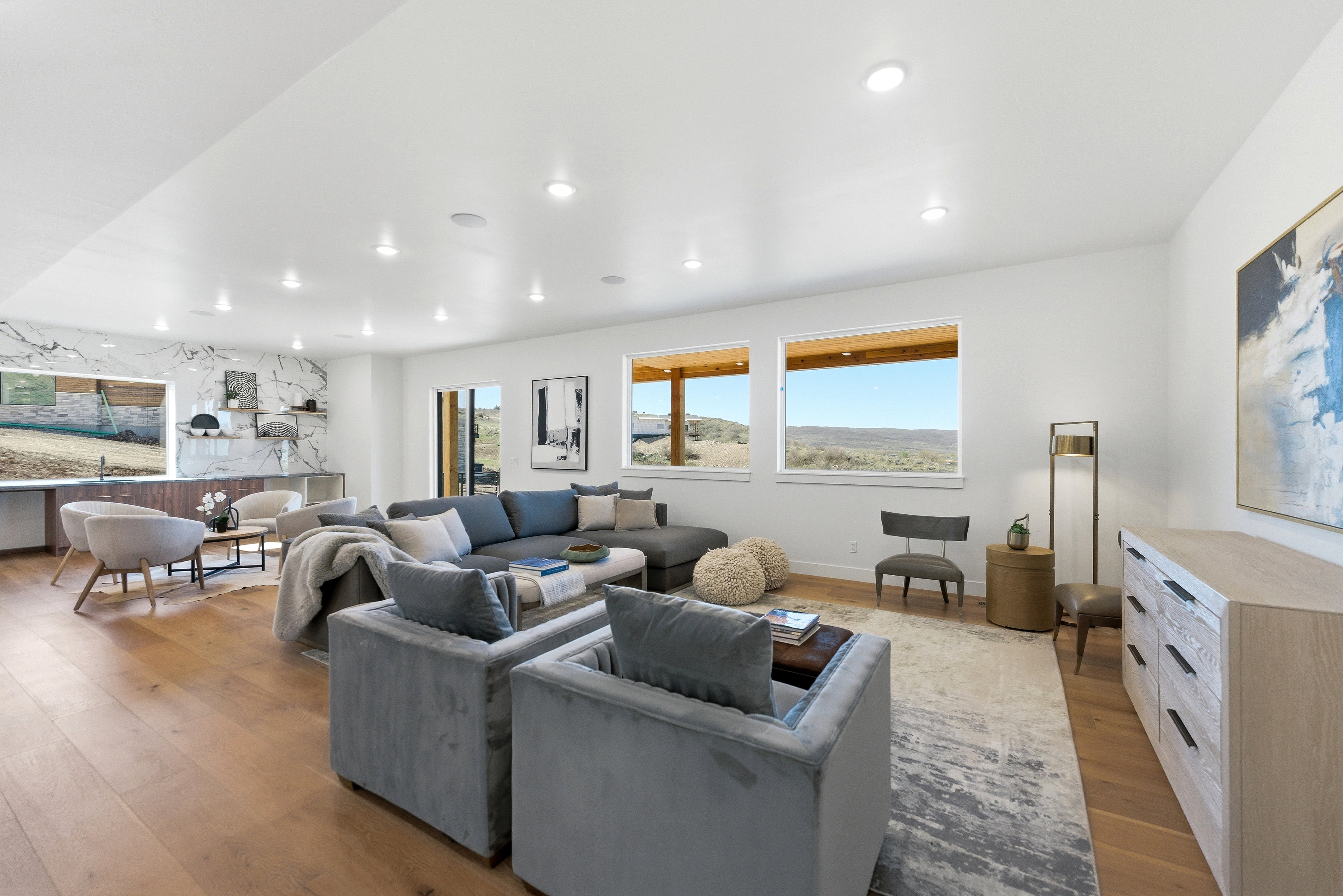 Spacious living area featuring wood-finish flooring, recessed lighting, and large windows with distant landscape