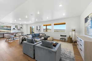 Spacious living area featuring wood-finish flooring, recessed lighting, and large windows with distant landscape