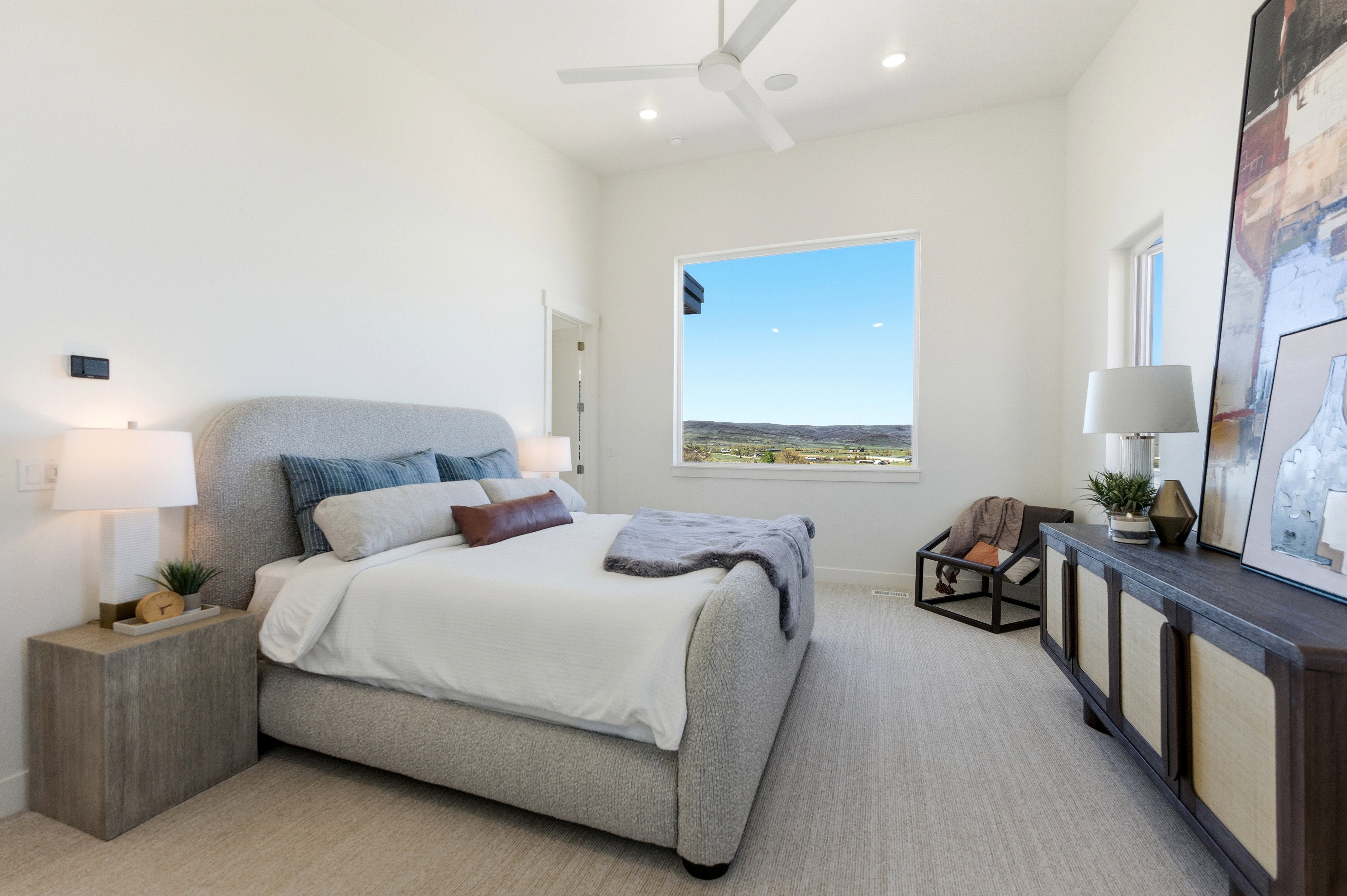 Primary bedroom features a large picture window, high ceilings, recessed lighting, and a ceiling fan