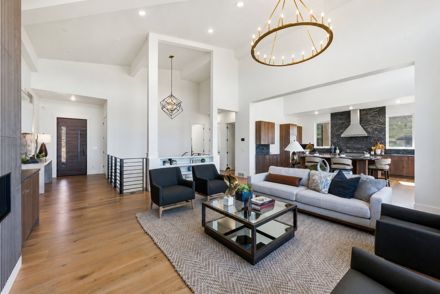 Spacious living area featuring high vaulted ceilings, light wood-finish flooring, and a contemporary linear chandelier