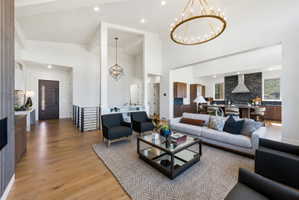 Spacious living area featuring high vaulted ceilings, light wood-finish flooring, and a contemporary linear chandelier