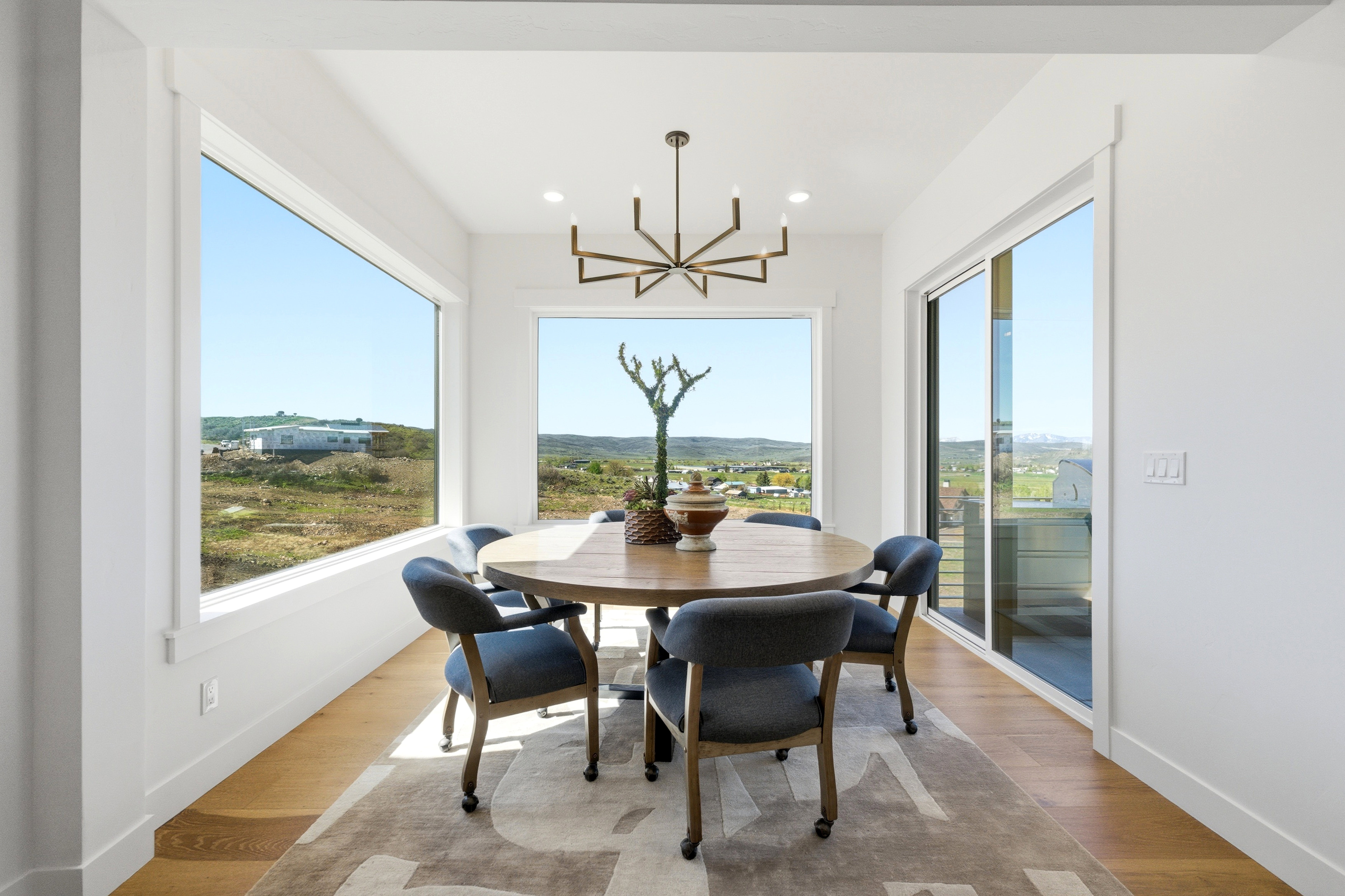 Bright dining area featuring wood-finish flooring, a contemporary chandelier, large picture windows, and a sliding glass door