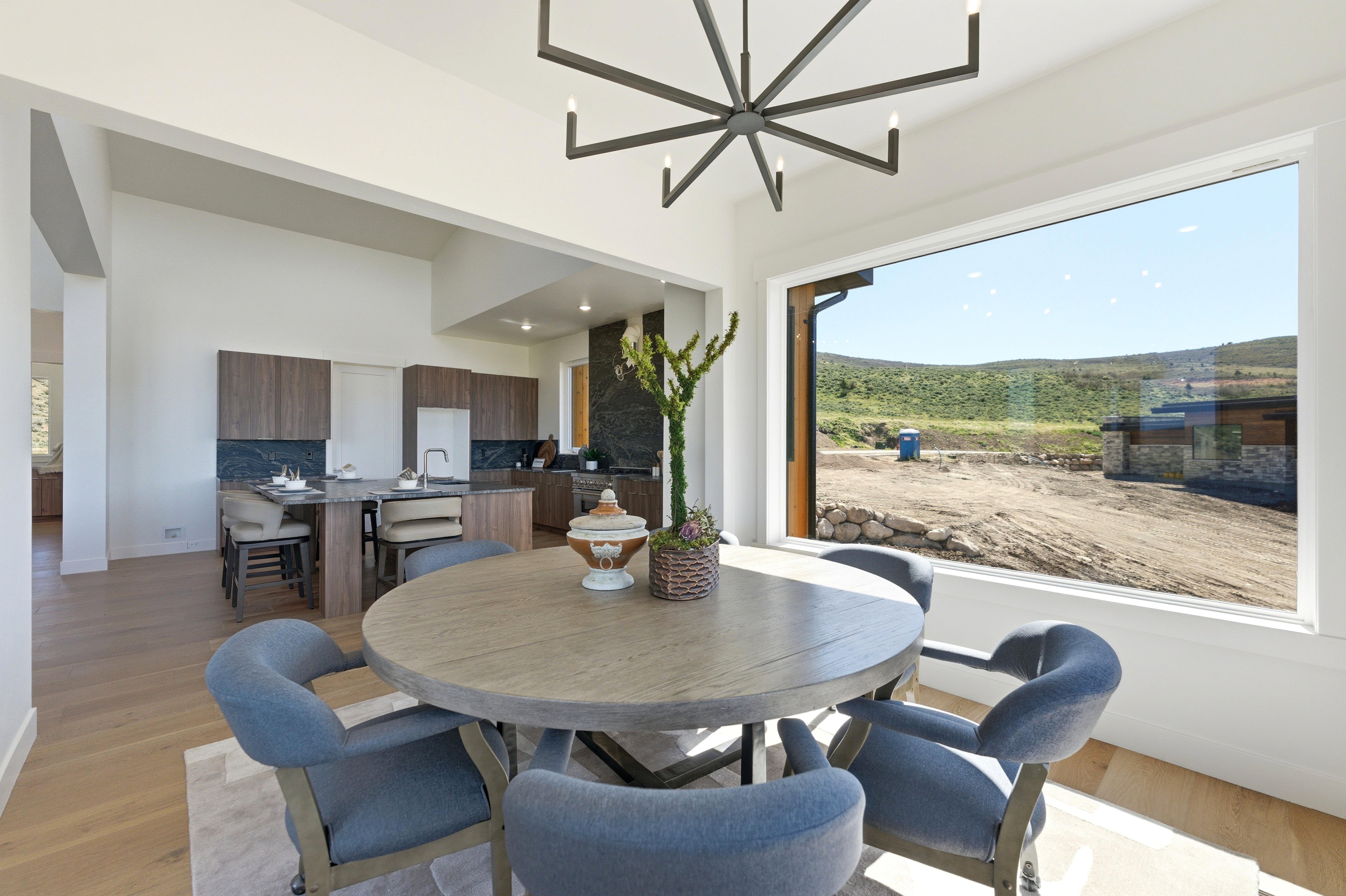 Expansive dining area featuring a contemporary chandelier, large picture window, and light wood-finish flooring
