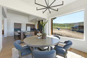Expansive dining area featuring a contemporary chandelier, large picture window, and light wood-finish flooring