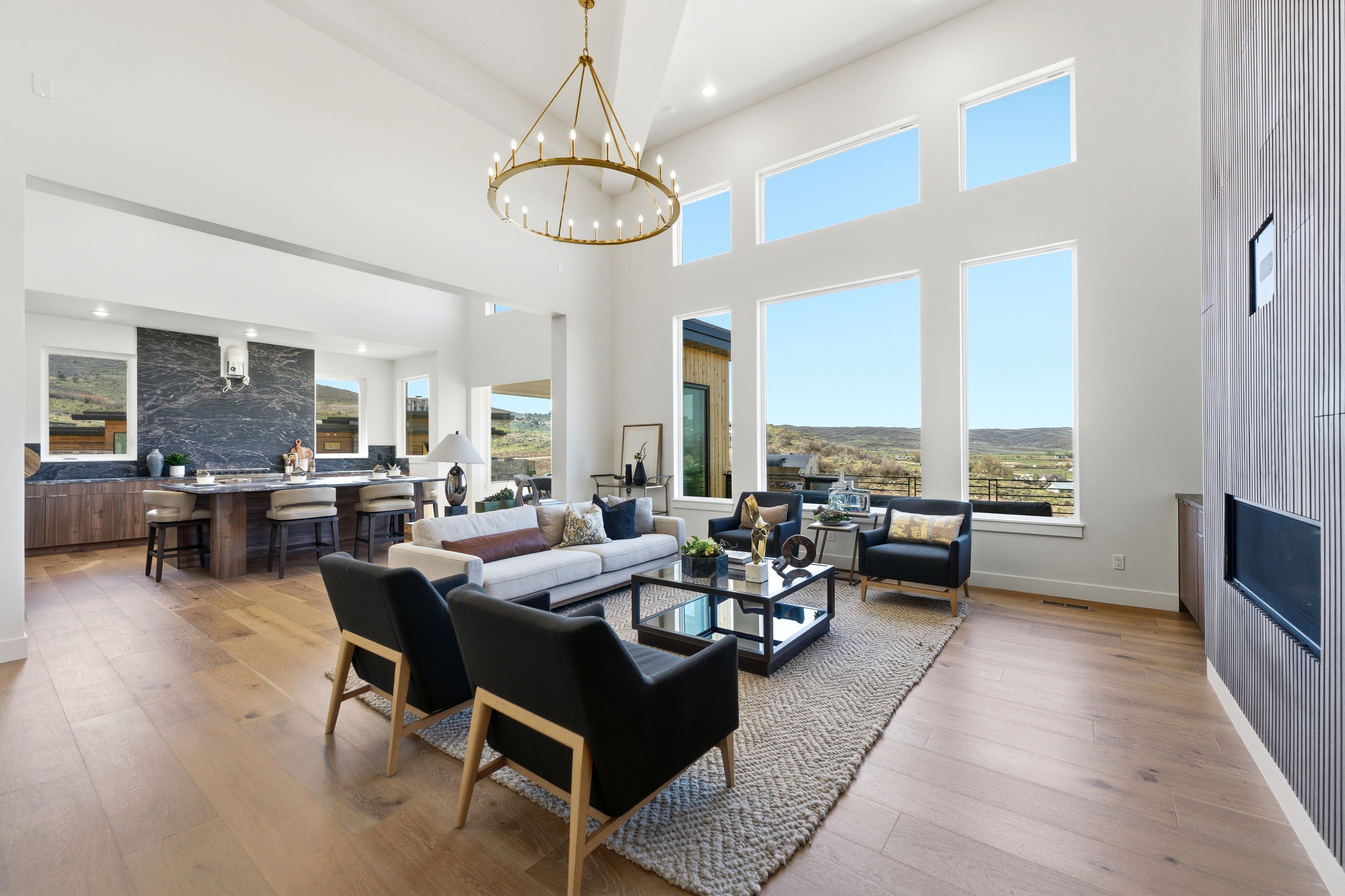 Expansive living space featuring soaring ceilings, a striking chandelier, and wood-finish flooring