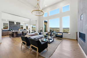 Expansive living space featuring soaring ceilings, a striking chandelier, and wood-finish flooring