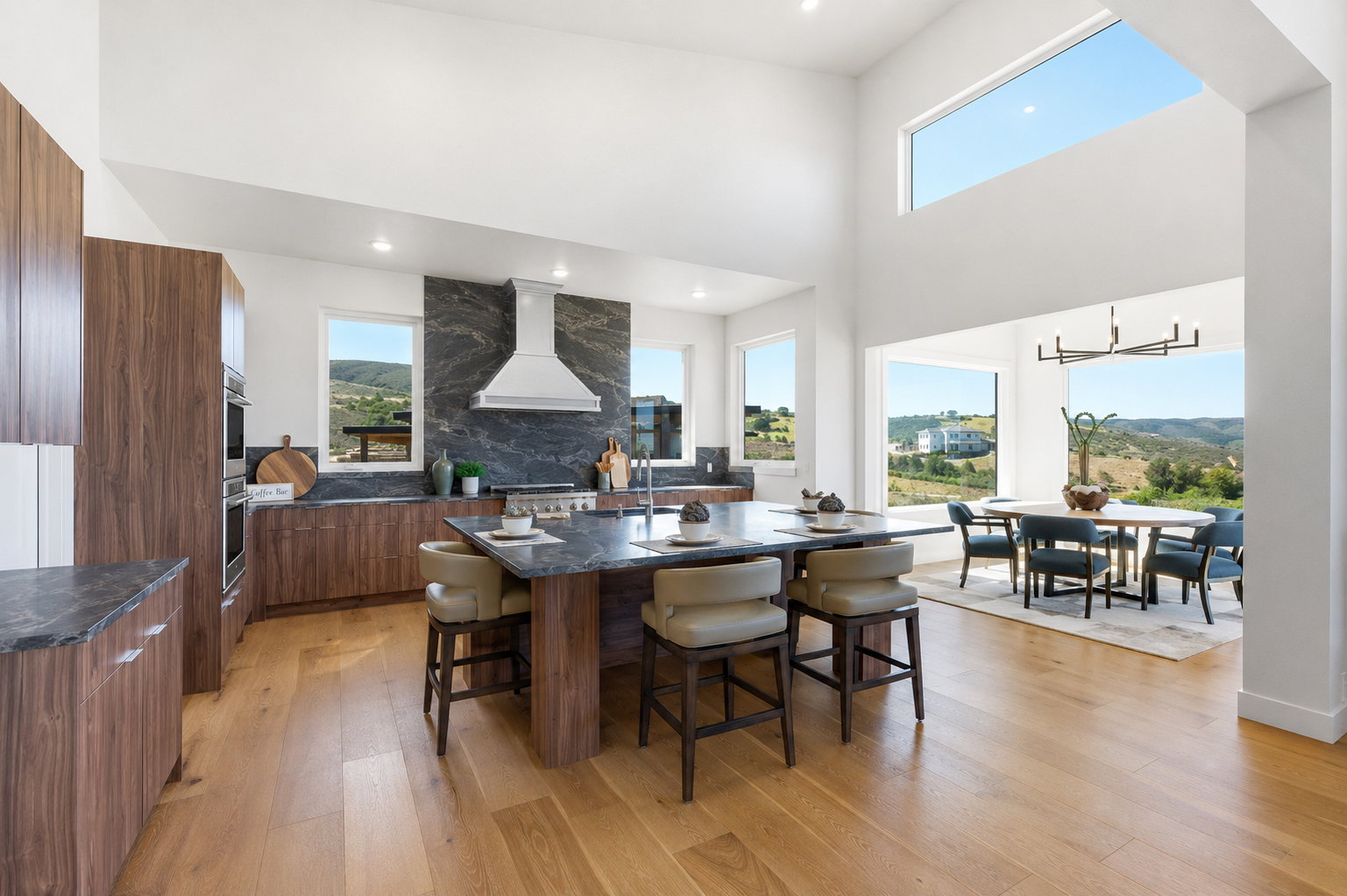 Spacious kitchen featuring an extended island with seating, integrated stainless steel appliances, and wood-finish cabinetry, hood virtually staged