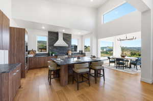 Spacious kitchen featuring an extended island with seating, integrated stainless steel appliances, and wood-finish cabinetry, hood virtually staged
