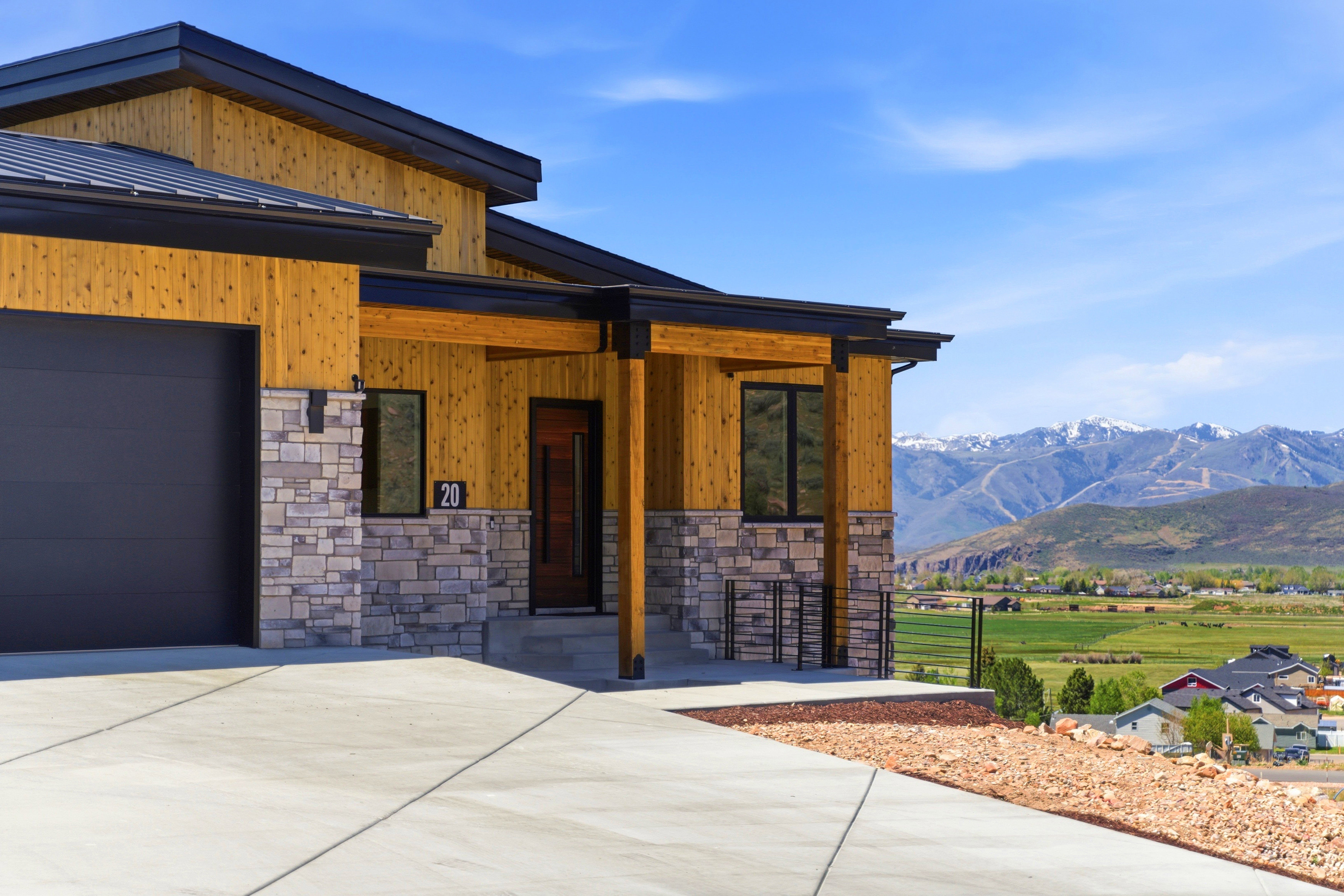 Contemporary exterior featuring wood siding, stone veneer accents, and a dark metal roof