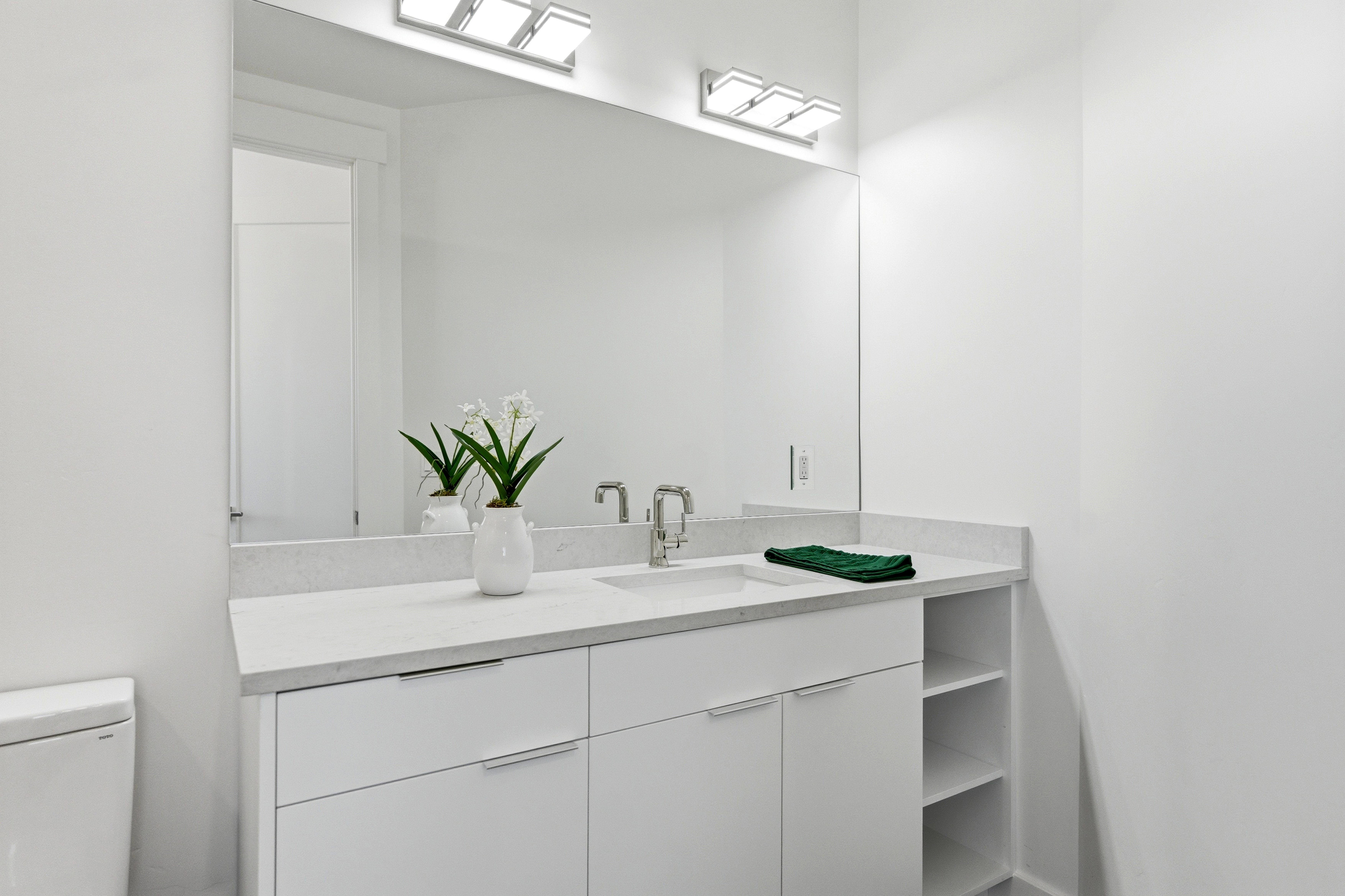 Bathroom vanity featuring an integrated sink, polished chrome faucet, and a large mirror