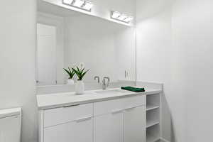 Bathroom vanity featuring an integrated sink, polished chrome faucet, and a large mirror