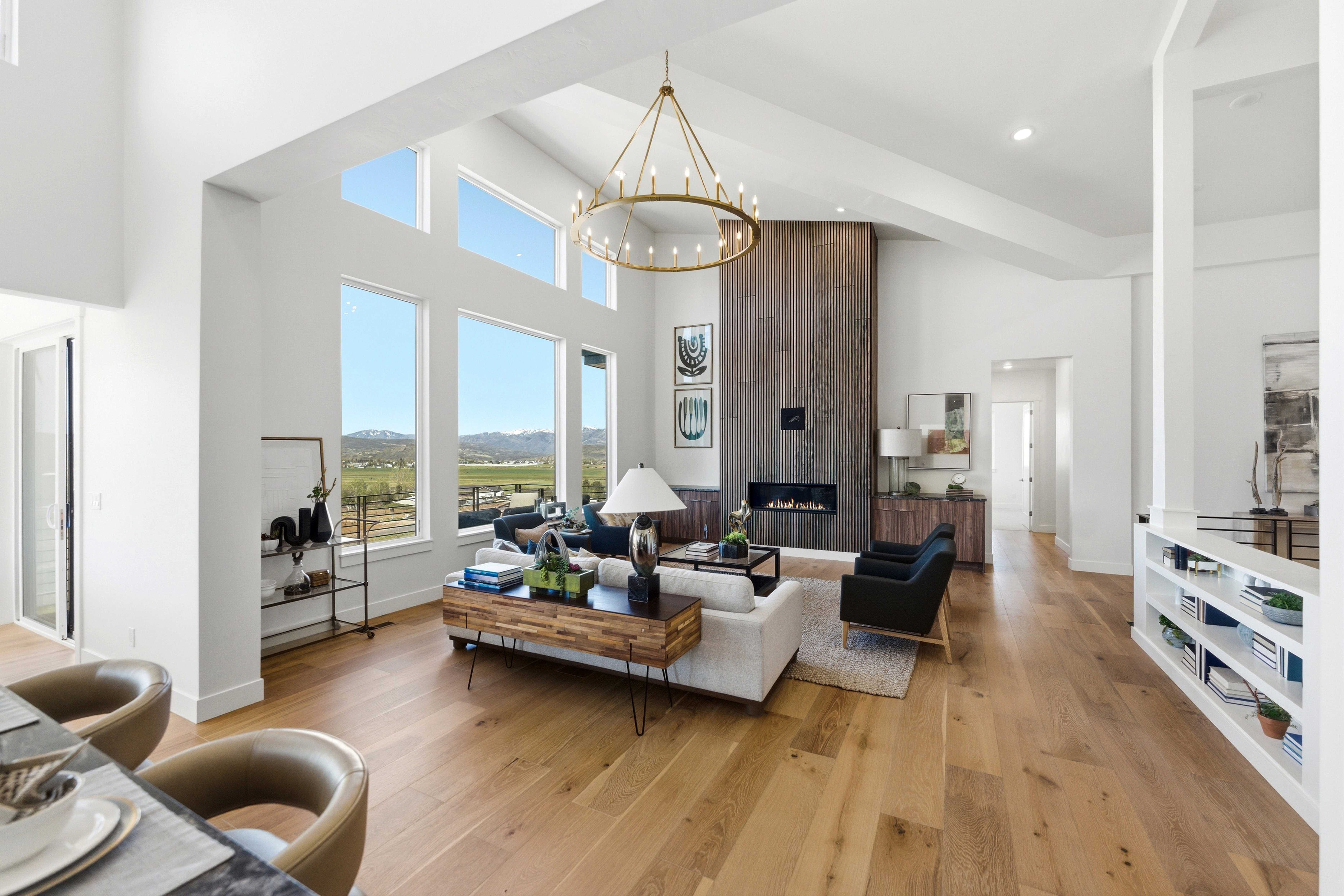 Spacious living area featuring a vaulted ceiling, wood-finish flooring, and a contemporary fireplace with a full-height wood panel surround