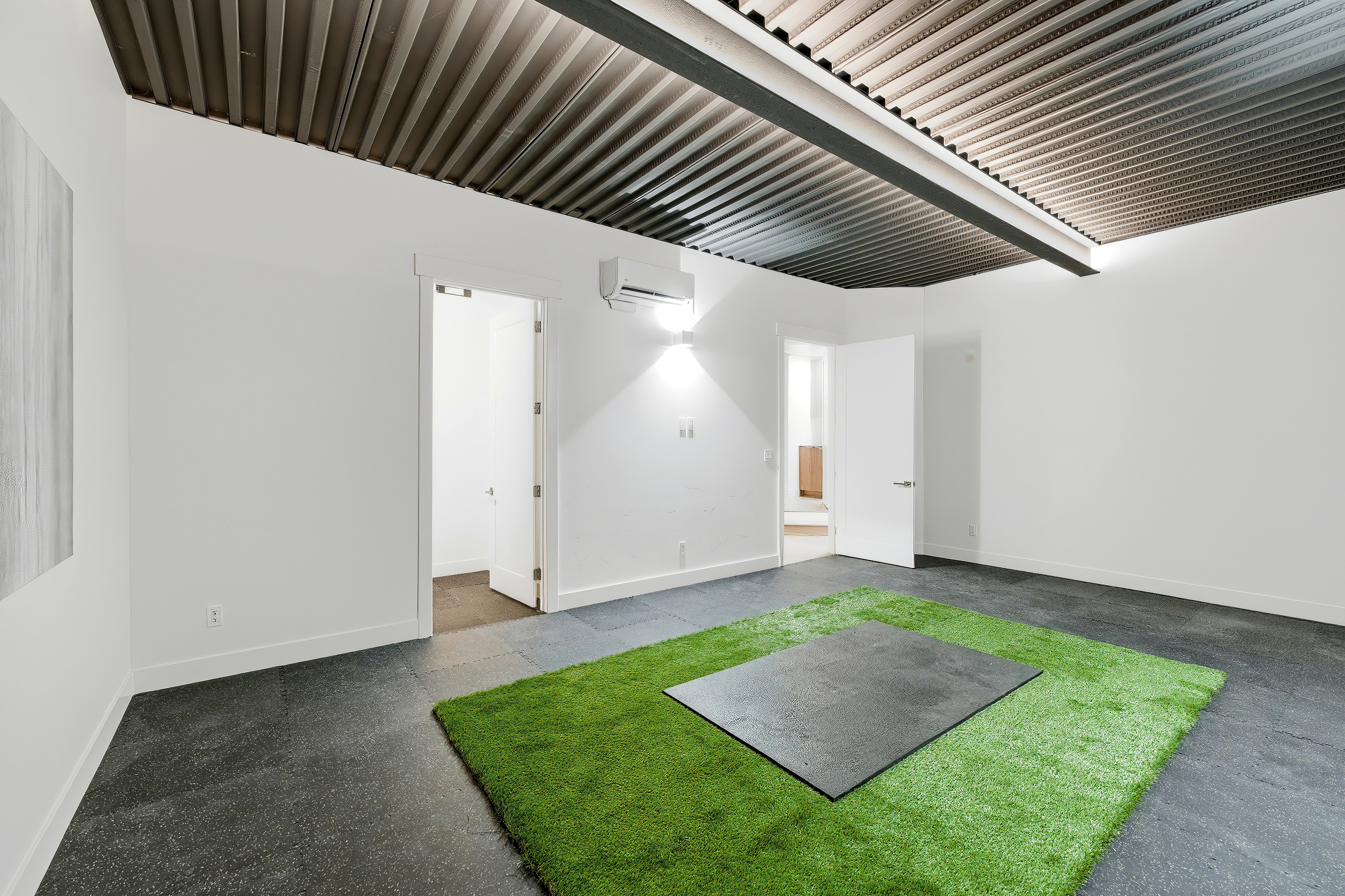 Spacious room featuring a corrugated metal ceiling, dark grey flooring, and white walls