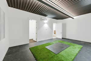 Spacious room featuring a corrugated metal ceiling, dark grey flooring, and white walls