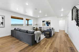 Spacious living area featuring expansive wood-finish flooring, recessed lighting, and large windows showcasing a mountain landscape