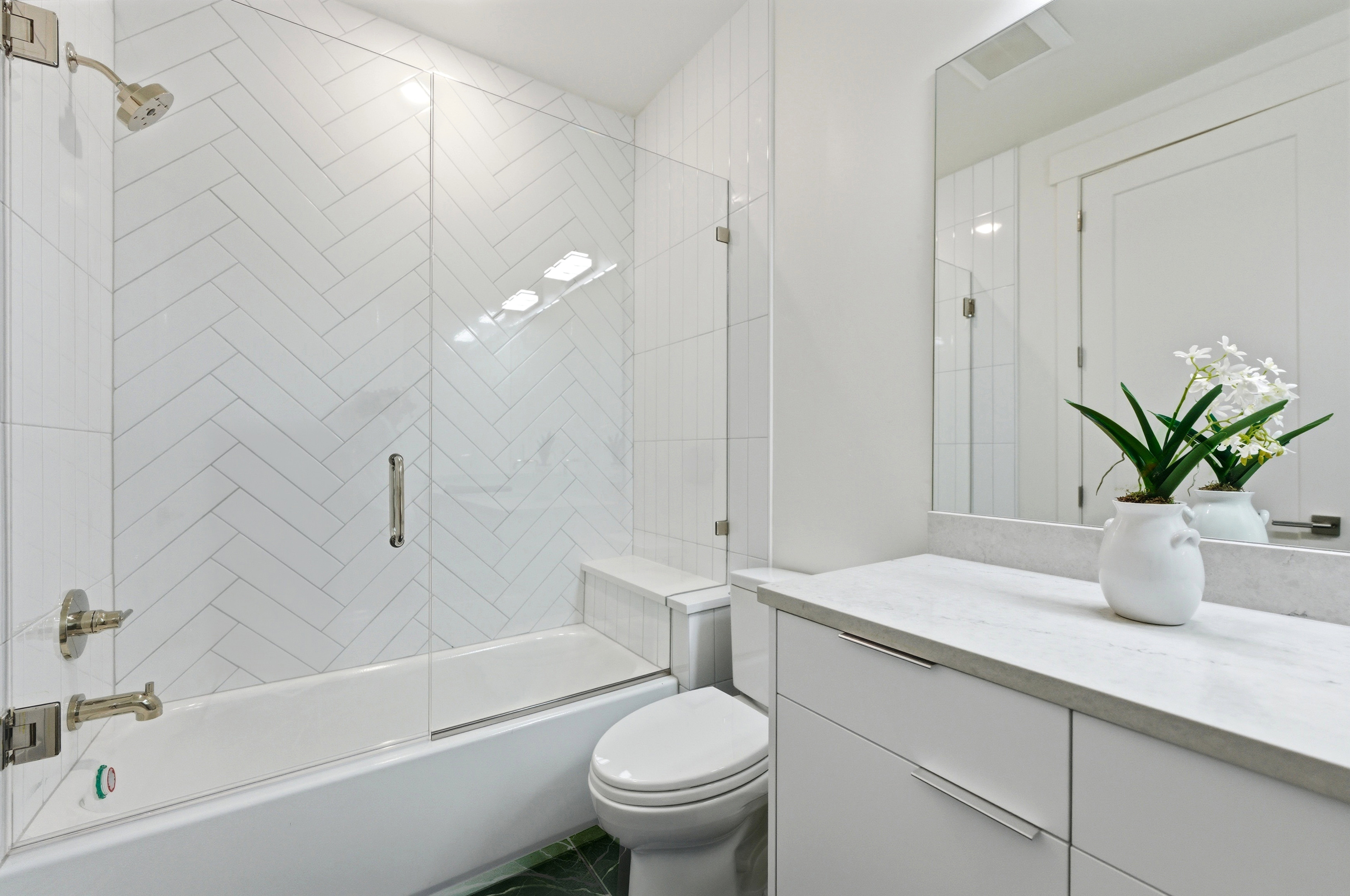 Bathroom featuring a full tub with a clear glass enclosure, white herringbone tile shower surround, and brushed nickel fixtures