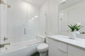 Bathroom featuring a full tub with a clear glass enclosure, white herringbone tile shower surround, and brushed nickel fixtures