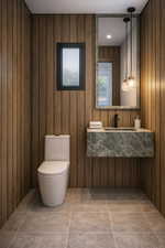 Bathroom featuring wood-finish paneling, a floating stone vanity with an integrated sink, a rectangular framed mirror, and a modern toilet. Rendering using AI as home is under construction.