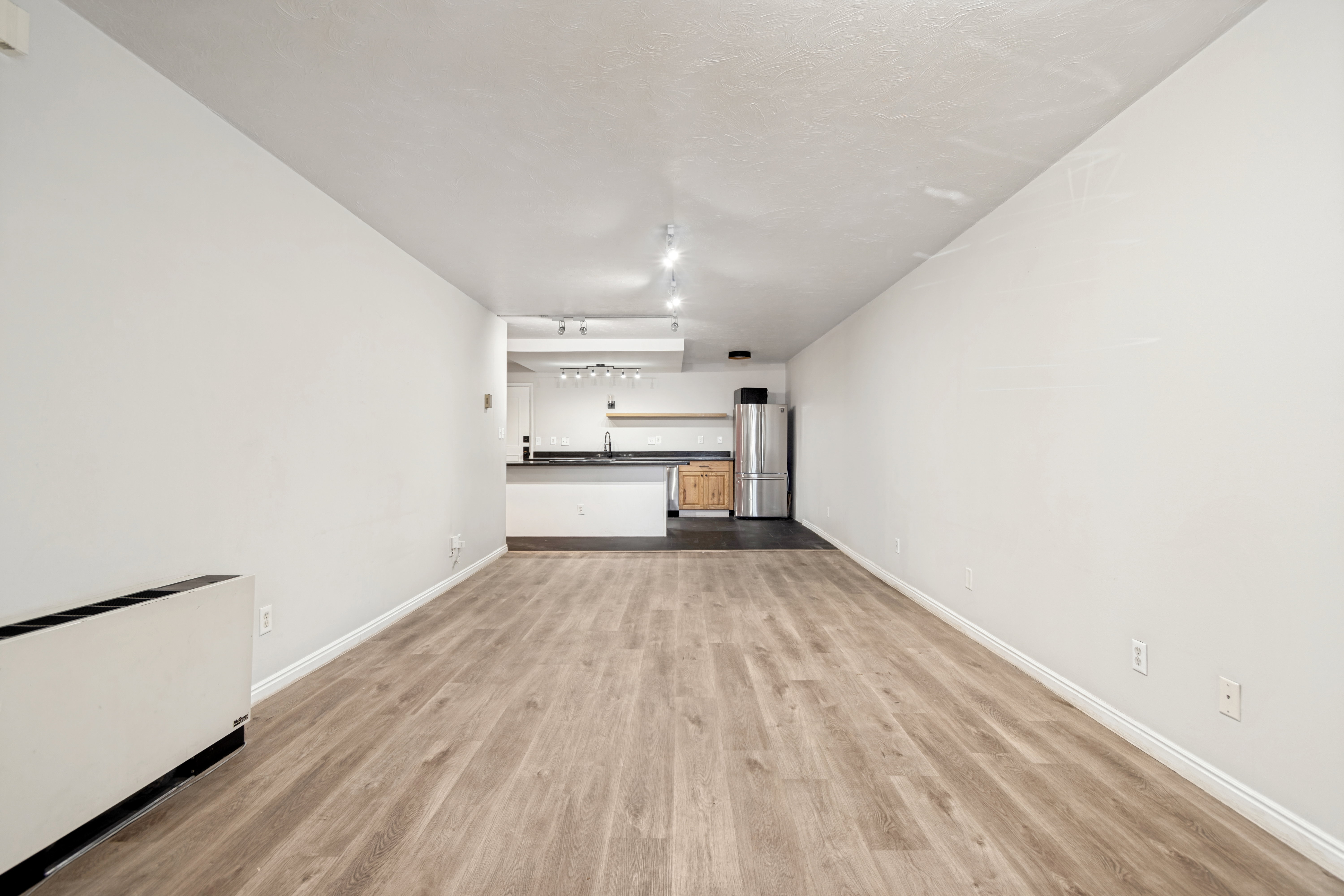 Spacious main living area featuring wood-finish flooring, white baseboards, and neutral wall tones