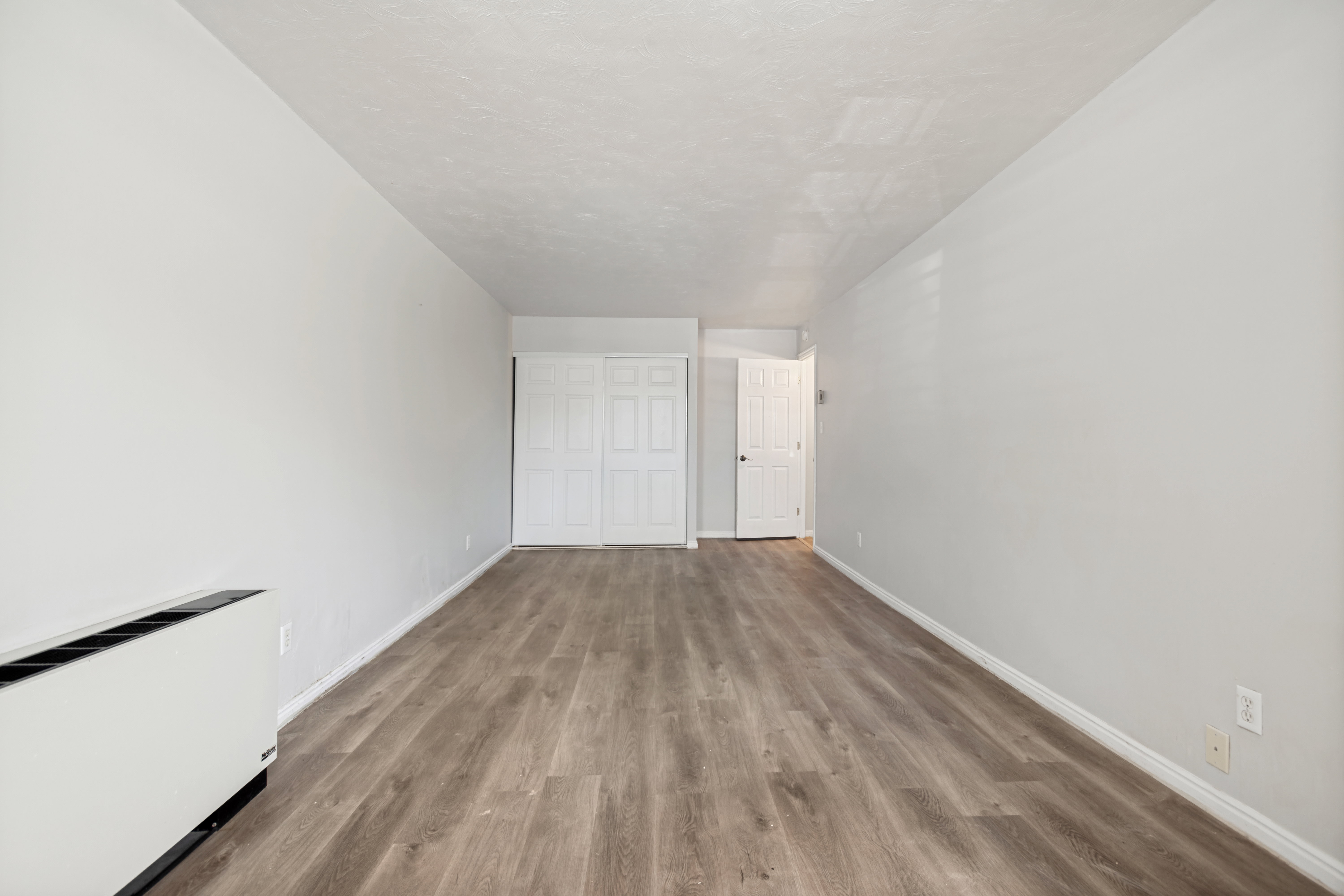 Expansive room featuring wood-finish flooring, light grey walls, and white trim