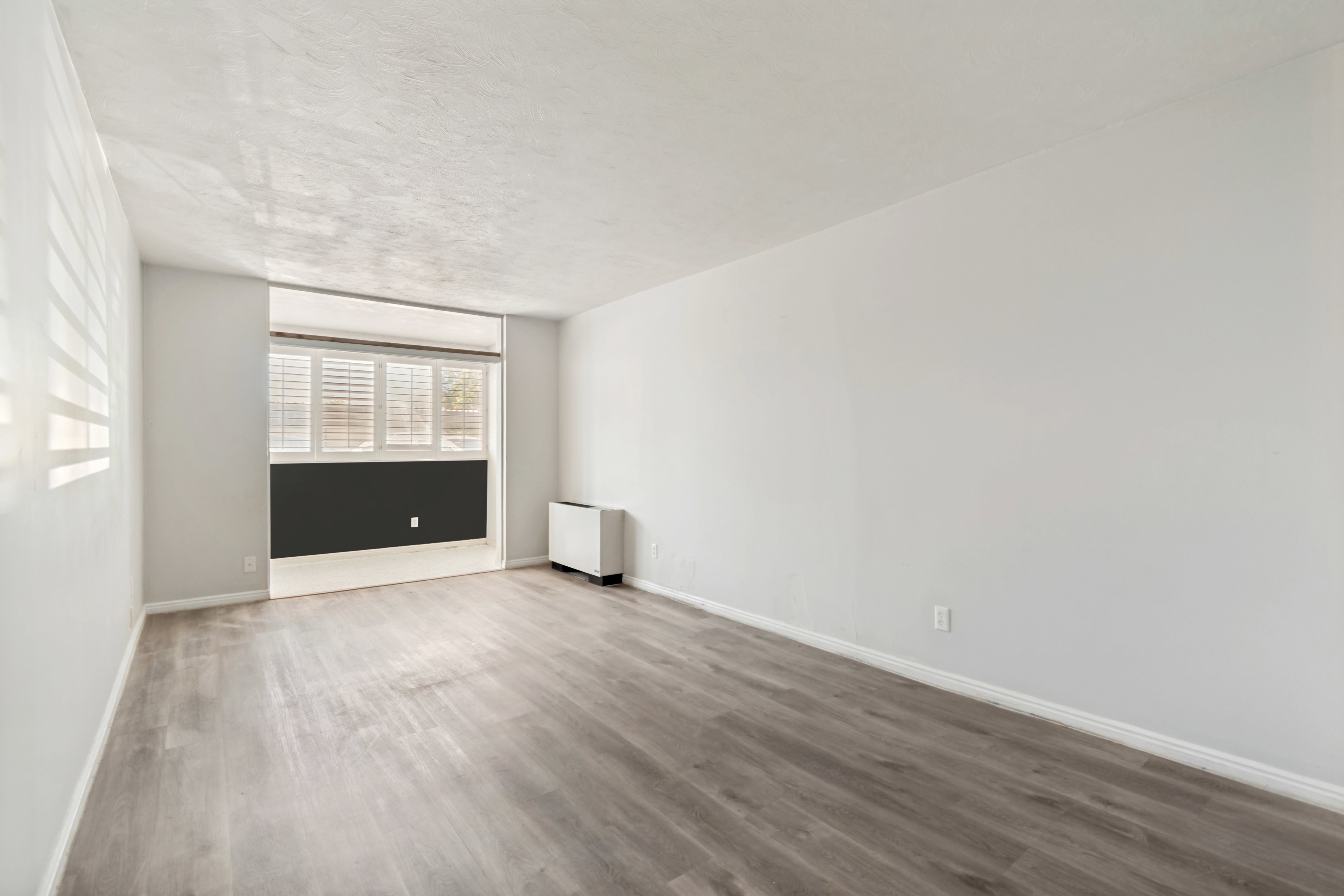 Spacious room featuring wood-finish flooring, white baseboards, and neutral wall paint