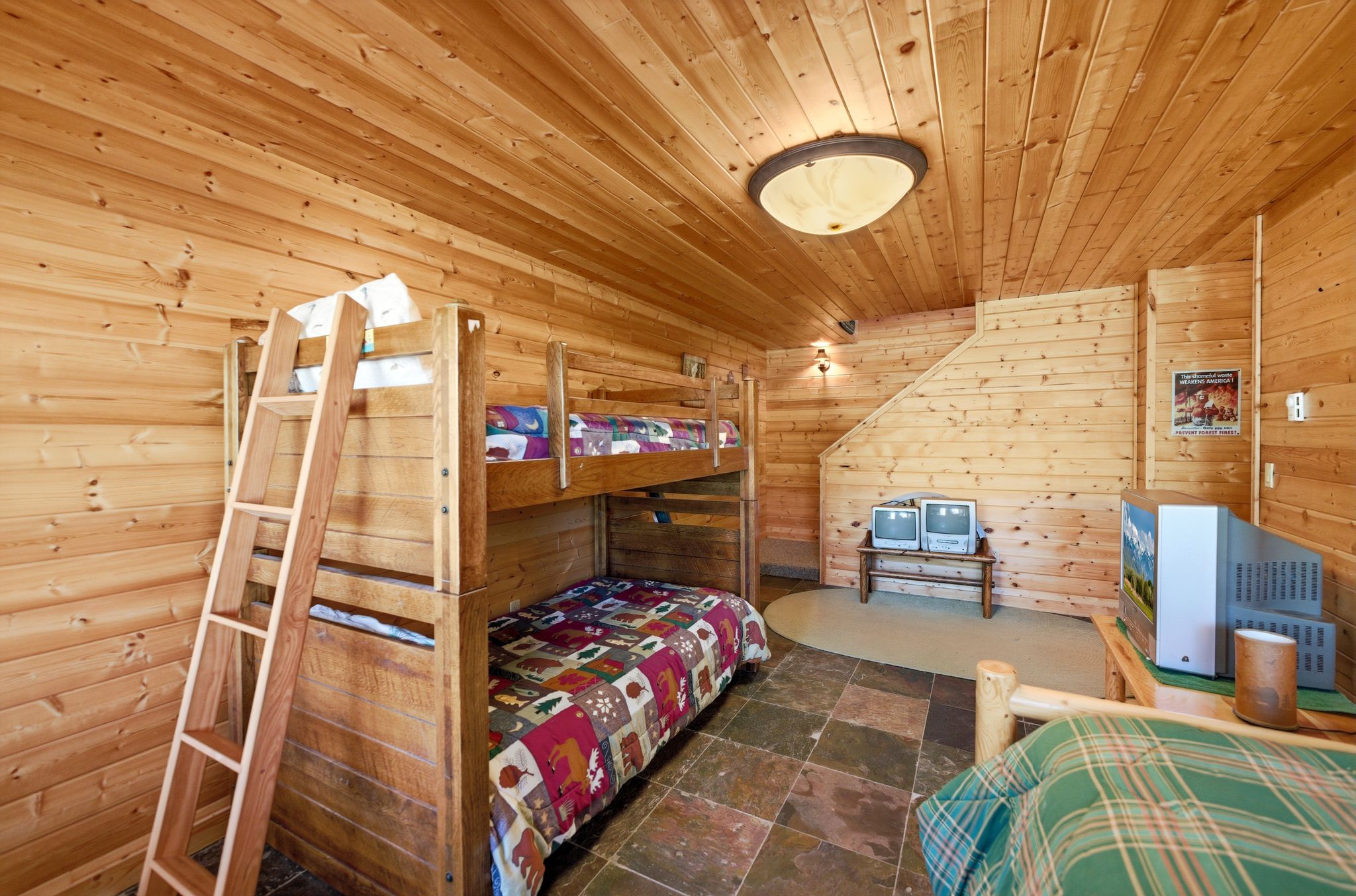 Wood-paneled room featuring slate tile flooring, a built-in bunk bed structure, and overhead flush-mount lighting
