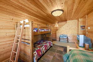 Wood-paneled room featuring slate tile flooring, a built-in bunk bed structure, and overhead flush-mount lighting