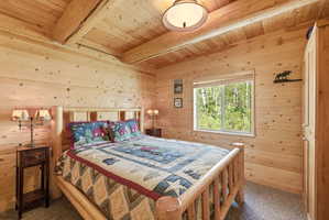 Wood-paneled room featuring exposed ceiling beams and a large window