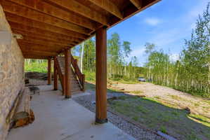 Expansive concrete patio with a natural stone wall and log support columns