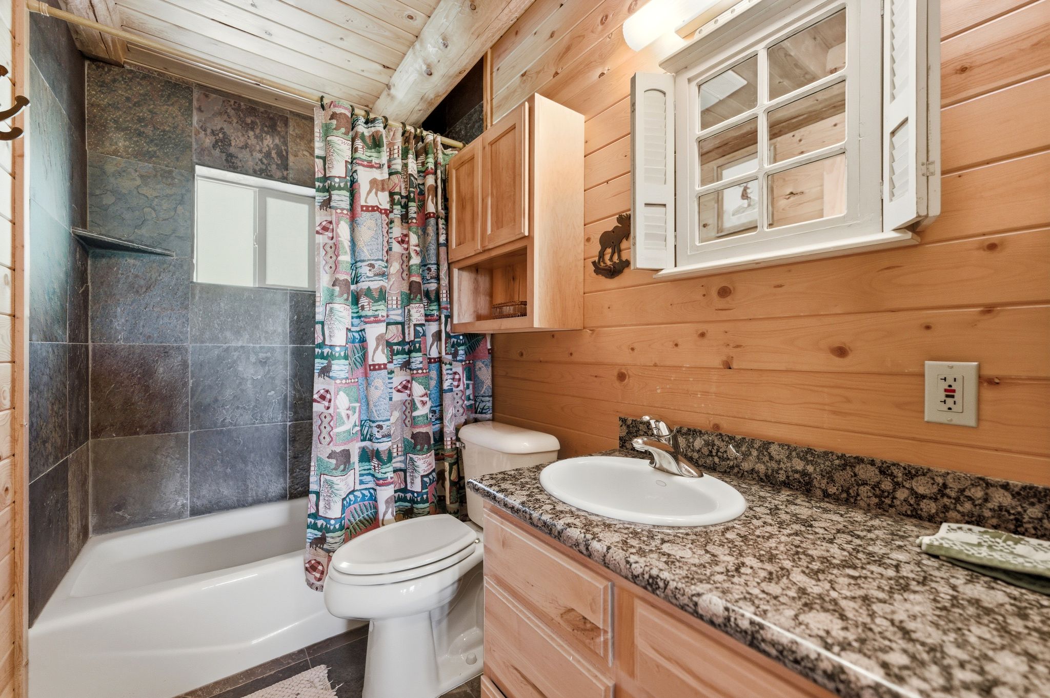 Bathroom featuring a tub/shower combination with dark tile surround, a built-in shelf, and a window