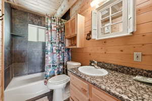 Bathroom featuring a tub/shower combination with dark tile surround, a built-in shelf, and a window