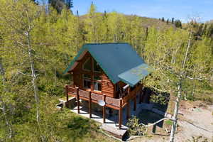 Log cabin exterior featuring a green metal roof, a full-length deck with wood railing, and a walk-out lower level