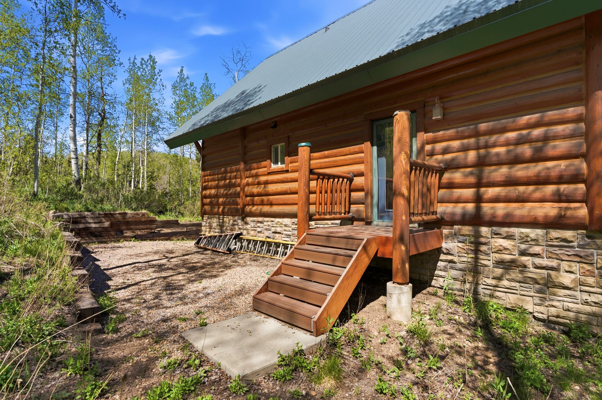Log-sided exterior with a light green metal roof