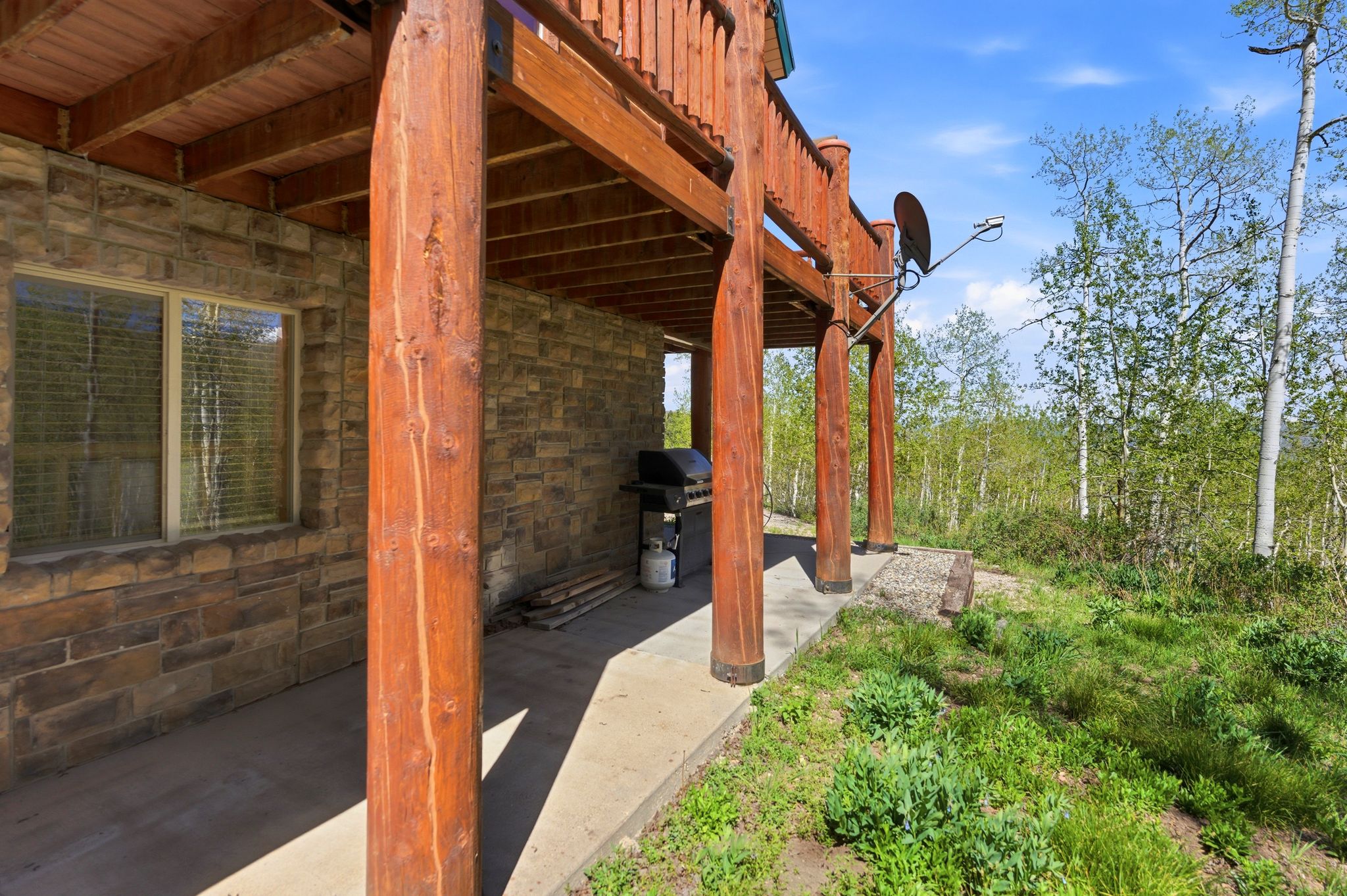 Covered patio with stone veneer siding and exposed wood beam supports