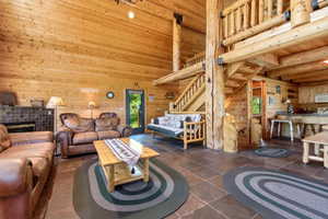 Spacious great room featuring extensive natural wood paneling and exposed log beams