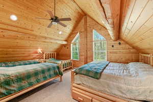 Attic room featuring extensive wood paneling and exposed log beams