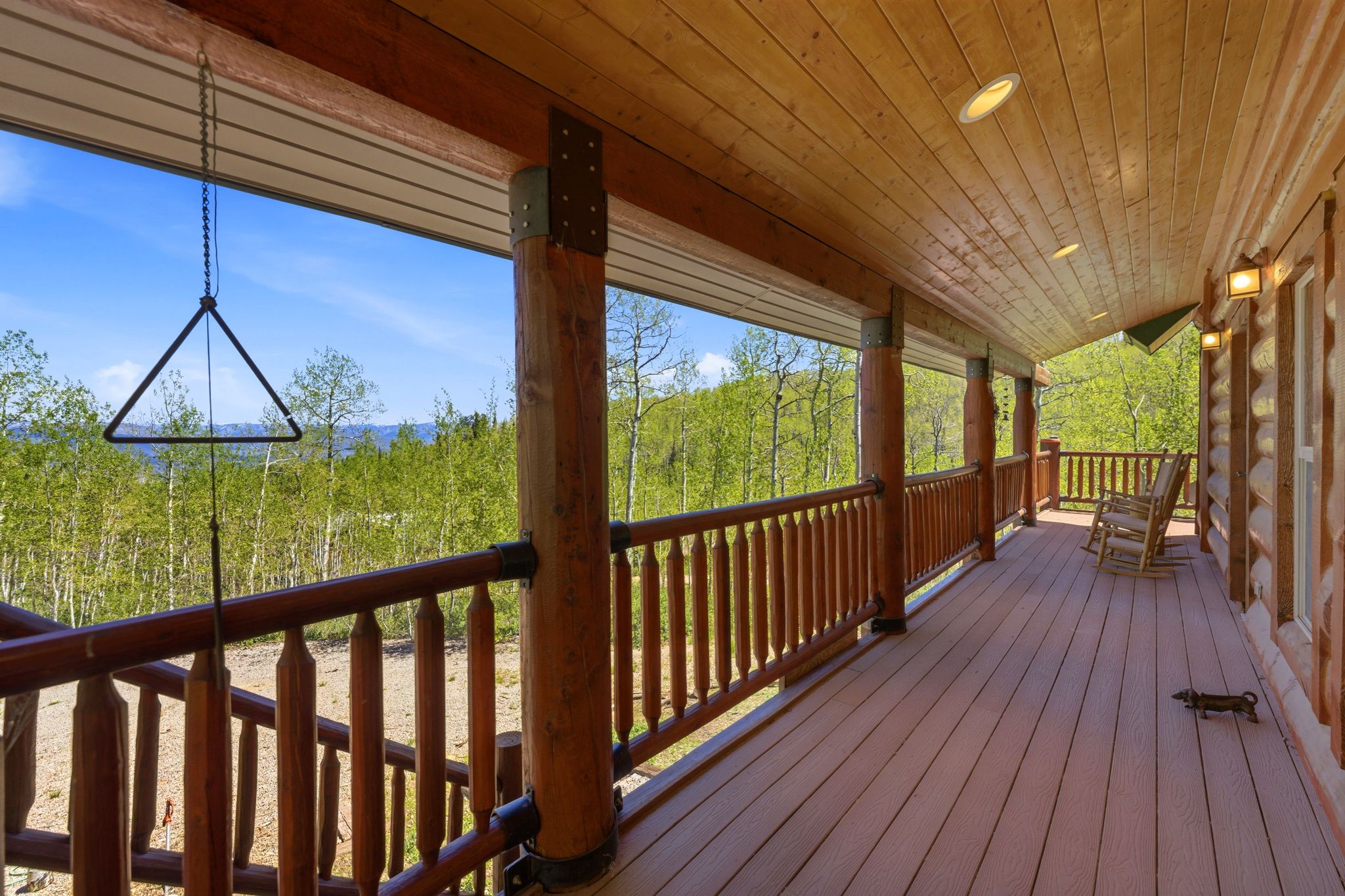 Expansive covered porch featuring a wood-finish floor, wood-paneled ceiling with recessed lighting, and log-style structural columns