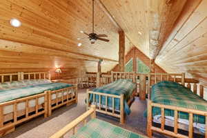 Loft space featuring extensive wood paneling and exposed log structural elements