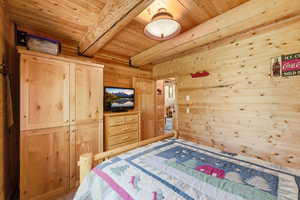 Room featuring natural wood plank walls and ceiling with exposed wood beams