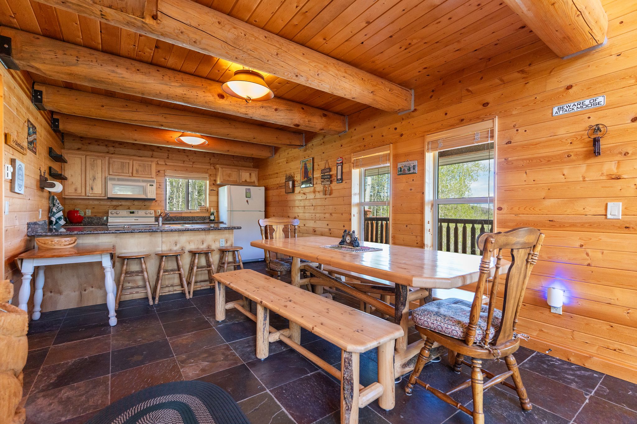 Spacious open-concept kitchen and dining area featuring natural wood paneling and exposed beam ceiling