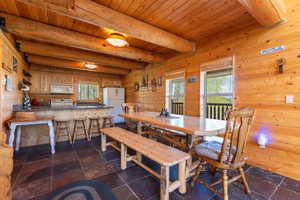 Spacious open-concept kitchen and dining area featuring natural wood paneling and exposed beam ceiling