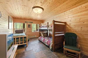 Room featuring extensive light-toned wood paneling on walls and ceiling, slate tile flooring, and multiple windows with wood slat blinds