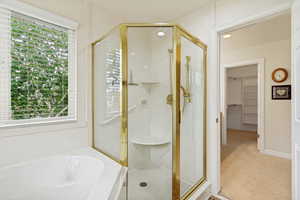 Corner glass-enclosed shower with gold-finish trim and integrated seating