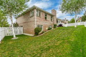 Expansive lawn with mature trees and a white picket fence enclosing the property