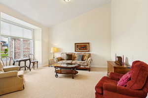 Living area featuring a vaulted ceiling and a broad bay window with a roller shade