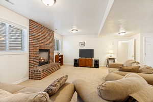 Spacious room featuring a brick fireplace with hearth, recessed windows, wall-to-wall carpeting, and overhead lighting