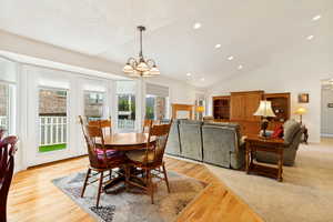Open-concept dining and living areas featuring a vaulted ceiling with recessed lighting