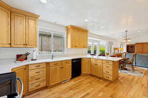 Open-concept kitchen featuring light wood cabinetry, white countertops, wood-finish flooring, a stainless steel sink, and recessed lighting
